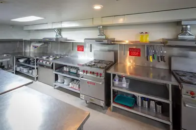 a large commercial kitchen with stainless steel appliances at HI Banff Alpine Centre - Hostel in Banff