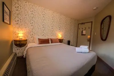 a bedroom with a large bed with two towels on it at HI Banff Alpine Centre - Hostel in Banff