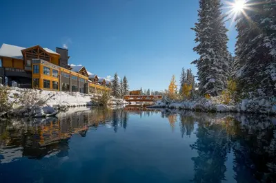a resort in the snow with a river at The Malcolm Hotel in Canmore