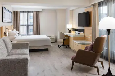 a hotel room with a bed and a desk and chairs at Delta Hotels by Marriott Grand Okanagan Resort in Kelowna
