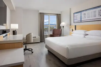 a hotel room with a white bed and a desk and a desk at Delta Hotels by Marriott Grand Okanagan Resort in Kelowna