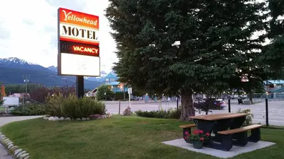 a sign for a motel with a bench and a sign at Yellowhead Motel in Valemount