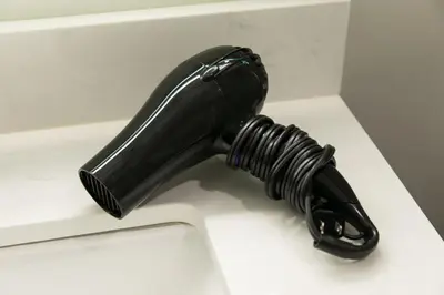 a black hair dryer sitting on a white sink at Days Inn by Wyndham 100 Mile House in One Hundred Mile House
