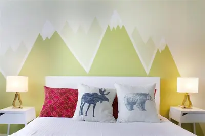 a bedroom with a bed with two pillows and mountains on the wall at Alpenglow Lodge by Bill in Whistler