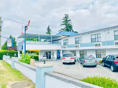 a building with cars parked in a parking lot at Happy Day Inn in Burnaby