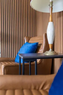 a table with a lamp and a couch with blue pillows at The Thompson Hotel in Kamloops