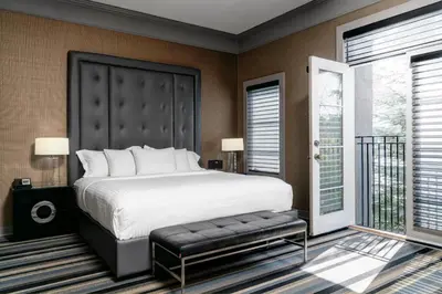 a bedroom with a large bed and a balcony at Hotel Arts Kensington in Calgary