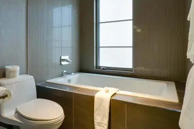 a bathroom with a tub and a toilet and a window at Hotel Arts Kensington in Calgary