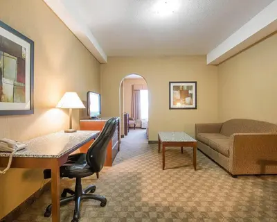a hotel room with a desk and a couch at Comfort Inn & Suites in Airdrie