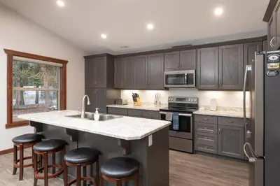 a kitchen with gray cabinets and a large island with bar stools at Aspen in Valemount
