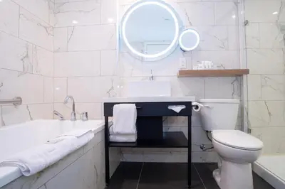 a white bathroom with a tub and a toilet and a sink at Sandman Signature Calgary Airport Hotel in Calgary