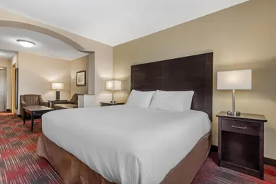 a hotel room with a large bed and a chair at Best Western Plus Red Deer Inn & Suite in Red Deer