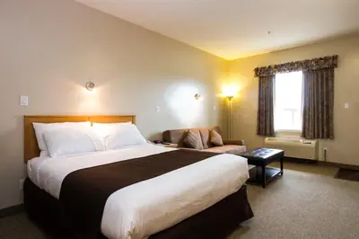 a hotel room with a large bed and a chair at West Country Inn in Drayton Valley