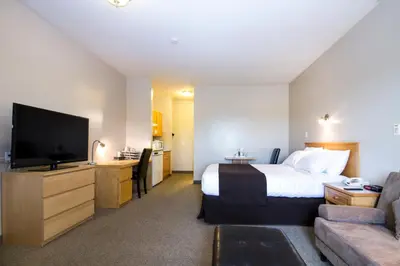 a hotel room with a bed and a flat screen tv at West Country Inn in Drayton Valley