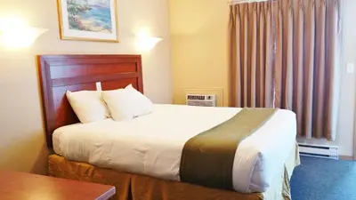 a hotel room with a bed and a window at Alpine Motel in Kamloops