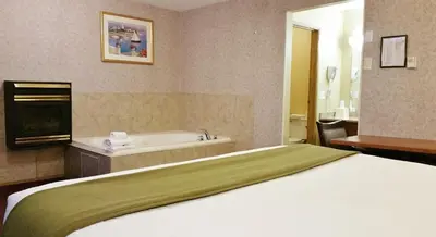a hotel room with a bed and a bath tub at Alpine Motel in Kamloops