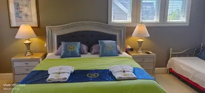 a bedroom with a bed with blue and green sheets and pillows at Sunny Island by White Rock B&B in White Rock