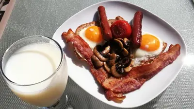a plate of breakfast food with bacon eggs mushrooms and a glass of milk at Sunny Island by White Rock B&B in White Rock