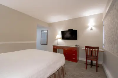 a hotel room with a bed and a television at Scott's Inn & Suites in Kamloops