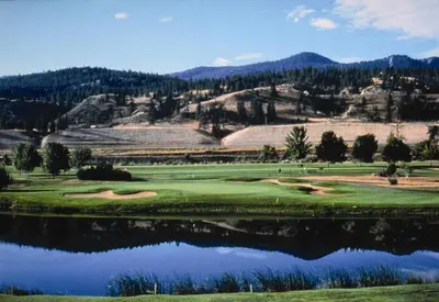 a golf course with a reflection in a lake at Scott's Inn & Suites in Kamloops