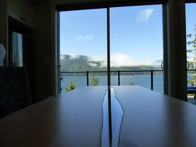 a large wooden table with a view of the water at Avatar by Eagle Reach Properties in Port Renfrew