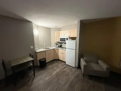 a small kitchen with a white refrigerator and a couch at Days Inn by Wyndham Stony Plain in Stony Plain