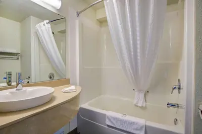 a bathroom with a sink and a tub and a mirror at Motel 6-Grande Prairie, AB in Grande Prairie