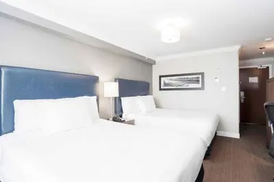 two beds in a hotel room with white sheets at Sandman Signature Prince George Hotel in Prince George