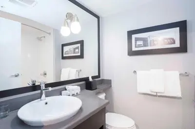 a white bathroom with a sink and a mirror at Sandman Signature Prince George Hotel in Prince George