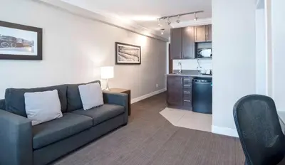 a living room with a couch and a kitchen at Sandman Signature Prince George Hotel in Prince George