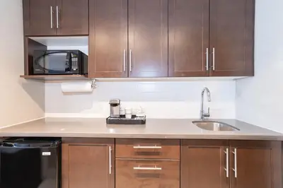 a kitchen with wooden cabinets and a sink and a microwave at Sandman Signature Edmonton South Hotel in Edmonton