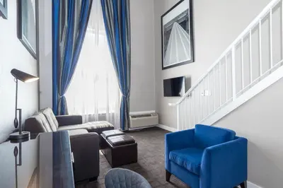 a living room with a couch and a blue chair at Sandman Signature Edmonton South Hotel in Edmonton