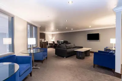 a living room with blue chairs and a couch at Sandman Signature Edmonton South Hotel in Edmonton