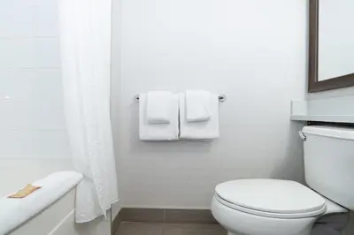 a white bathroom with a toilet and towels at Sandman Hotel & Suites Calgary South in Calgary