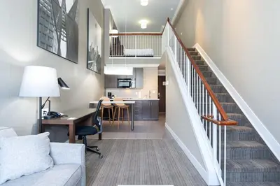 a living room with a staircase leading to a kitchen at Sandman Hotel & Suites Calgary South in Calgary