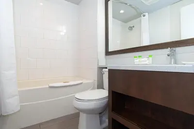 a bathroom with a toilet and a tub and a sink at Sandman Hotel & Suites Calgary South in Calgary