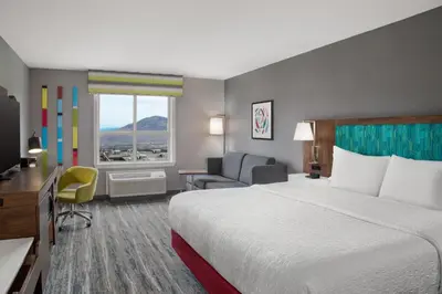 a hotel room with a bed and a chair and a window at Hampton Inn by Hilton Kamloops in Kamloops