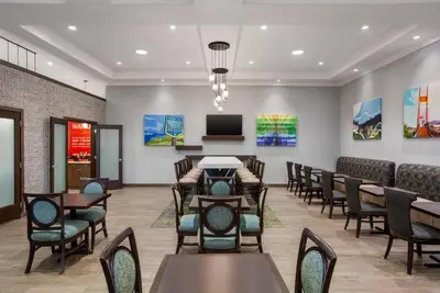 a waiting room with tables and chairs and a tv at Hampton Inn by Hilton Kamloops in Kamloops