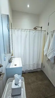 a white bathroom with a sink and a shower at The Cube Cow Bay Suite in Cowichan Bay