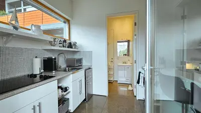 a kitchen with white counters and a window and a sink at The Cube Cow Bay Suite in Cowichan Bay