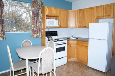 a small kitchen with a table and a white refrigerator at Spanish Villa Resort in Penticton
