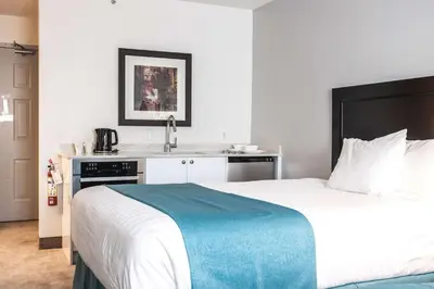 a bedroom with a large bed and a sink at Ramada by Wyndham Surrey/Langley in Surrey