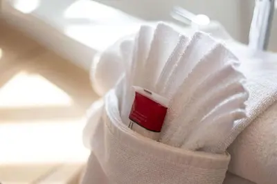 a white towel on a couch with a red book at Ramada by Wyndham Surrey/Langley in Surrey