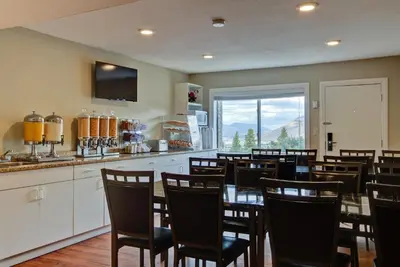 a dining room with chairs and a table and a kitchen at Knights Inn Kamloops in Kamloops