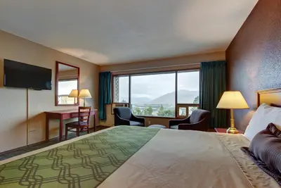 a hotel room with a bed and a desk and a window at Knights Inn Kamloops in Kamloops