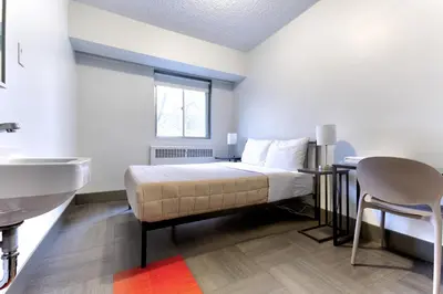 a bedroom with a bed and a sink and a bathroom at HI Edmonton - Hostel in Edmonton