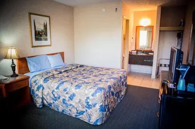 a hotel room with a bed and a television at Langley Hwy Hotel in Langley