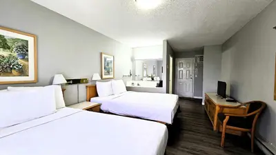 a hotel room with two beds and a desk at Okanagan Seasons Resort in Kelowna