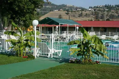 a pool with white tables and chairs next to a building at Okanagan Seasons Resort in Kelowna