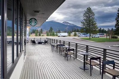 a balcony with tables and chairs and a clock on a building at Marmot Lodge Jasper in Jasper